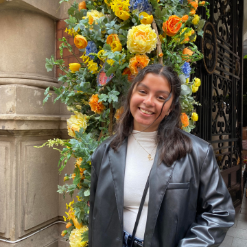 A Student posing in front of flowers